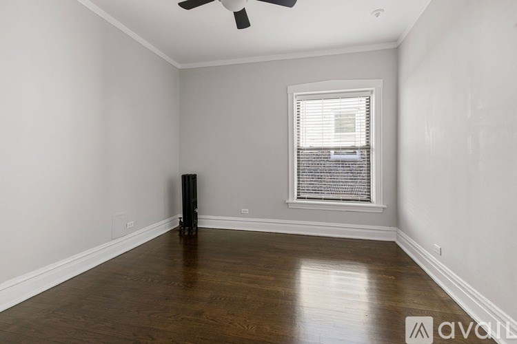 A room with a ceiling fan, a window with blinds, and a wooden floor.