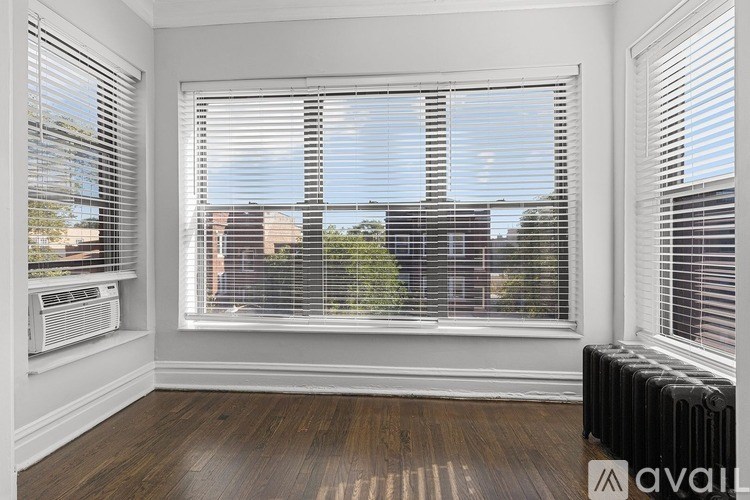 A room with a window covered in blinds and a radiator on the floor.