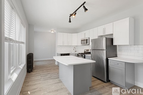 A kitchen with white cabinets and a wooden floor.