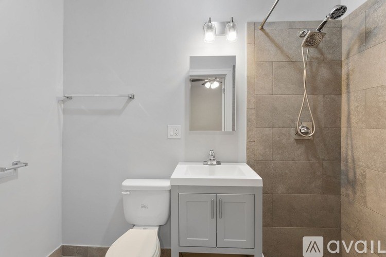 A bathroom with a toilet, sink, mirror, and shower.