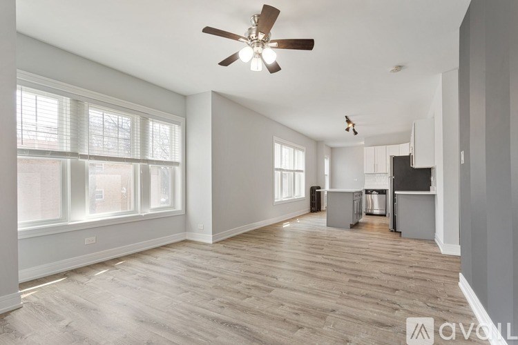 A spacious room with a ceiling fan and wooden flooring.