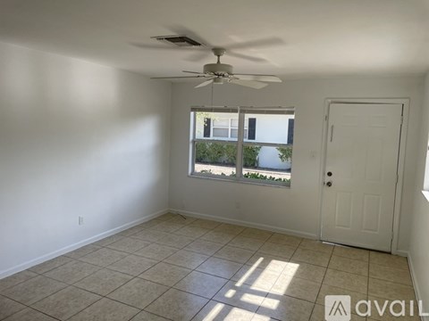 A tiled hallway with a door on the right and a window on the left.