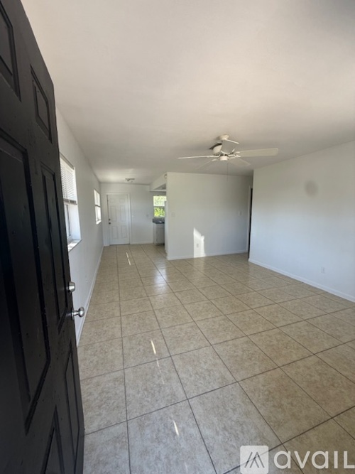 A room with beige tiled flooring and white walls, with a door on the right.