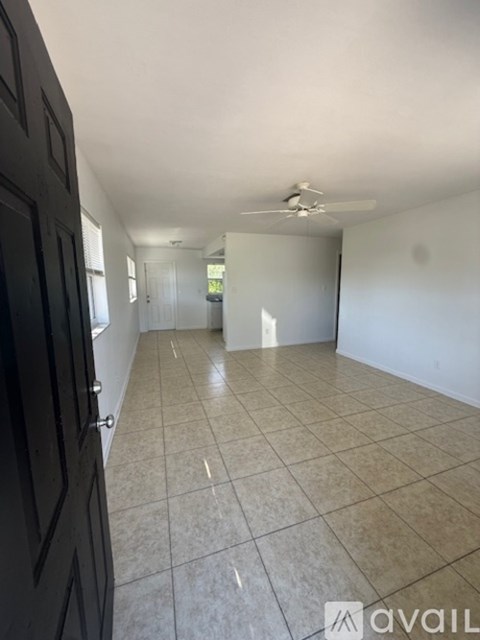 A room with beige tiled flooring and white walls, with a door on the right.