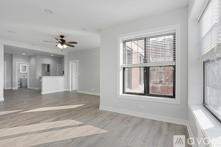 A spacious room with a ceiling fan and large windows.