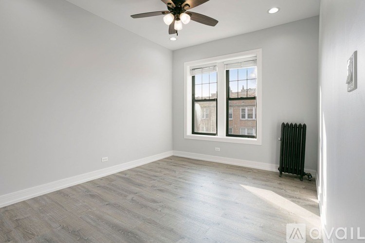 A spacious room with a ceiling fan, a window, and a radiator on the floor.