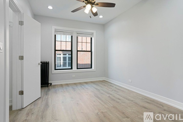 A room with a ceiling fan and a window with a black radiator beneath it.