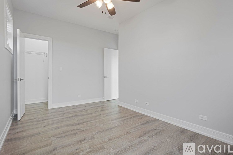 A spacious room with a ceiling fan and light, and a wooden floor.