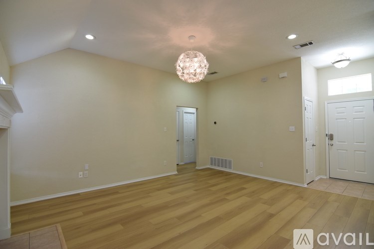 A room with wooden floors and a chandelier hanging from the ceiling.