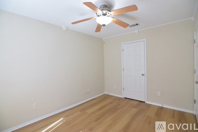 A room with a ceiling fan and wooden flooring.