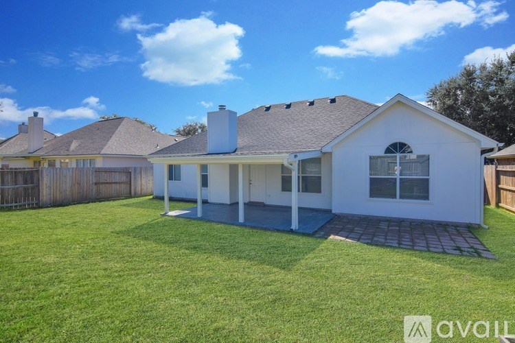 A white house with a brown roof and a fence in the front yard.