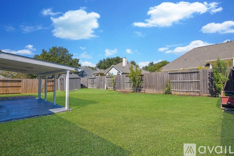 A backyard with a trampoline and a covered patio area.