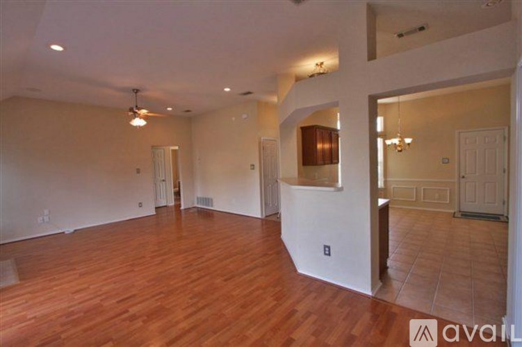 A spacious room with wooden floors and a ceiling fan.