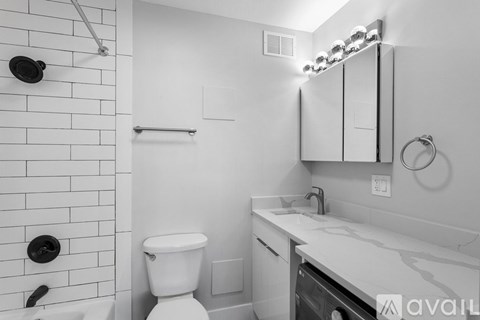 A white bathroom with a toilet, sink, and shower.