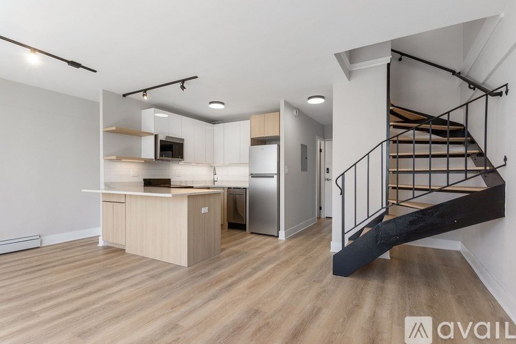 A modern kitchen with a wooden floor and a staircase.