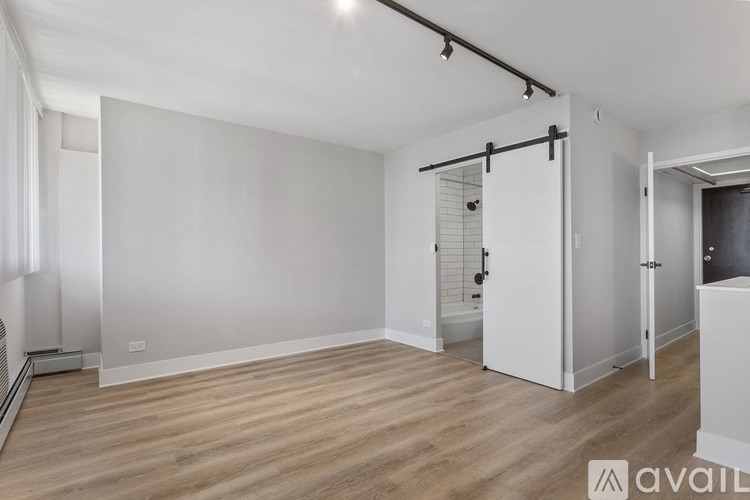 A spacious room with wooden flooring and white walls.