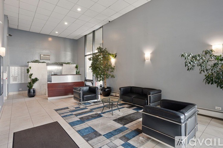A waiting room with a black leather couch and a blue and white rug.