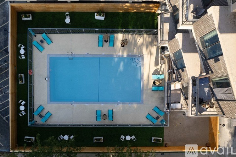 An aerial view of a swimming pool surrounded by lounge chairs and umbrellas.