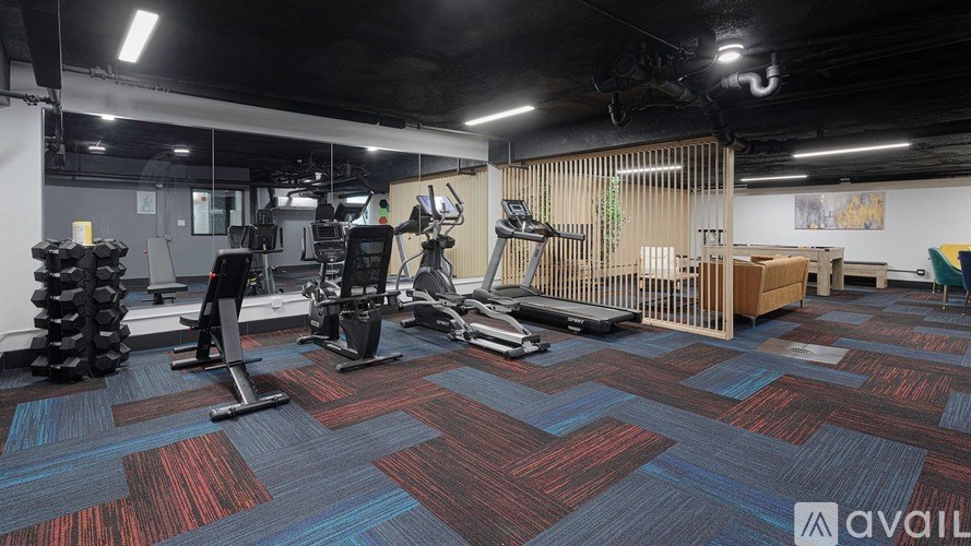 A gym with a variety of equipment including treadmills, weights, and exercise machines.