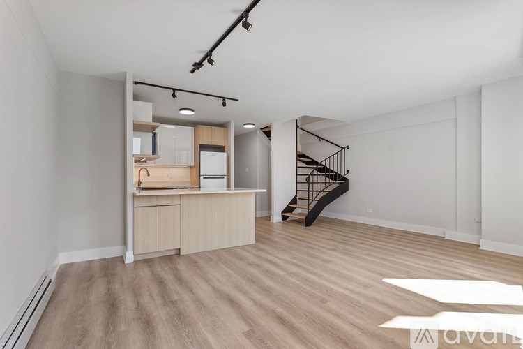 A spacious room with wooden flooring and a staircase.