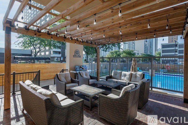 A patio with a pool in the background and a table and chairs under a roof.
