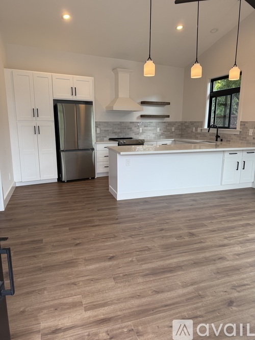 A kitchen with white cabinets and a wooden floor.