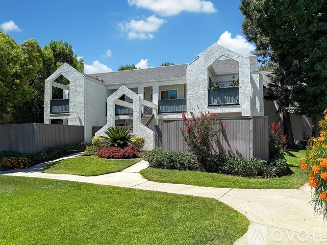 A white house with a grey roof and a green lawn in front.