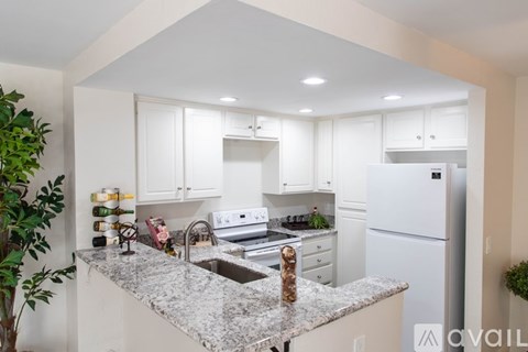 A kitchen with white cabinets and a marble countertop.