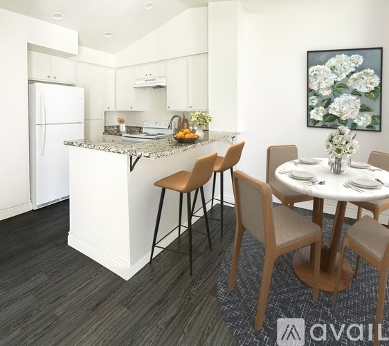 A kitchen with a white fridge, a white dining table with chairs and a painting on the wall.
