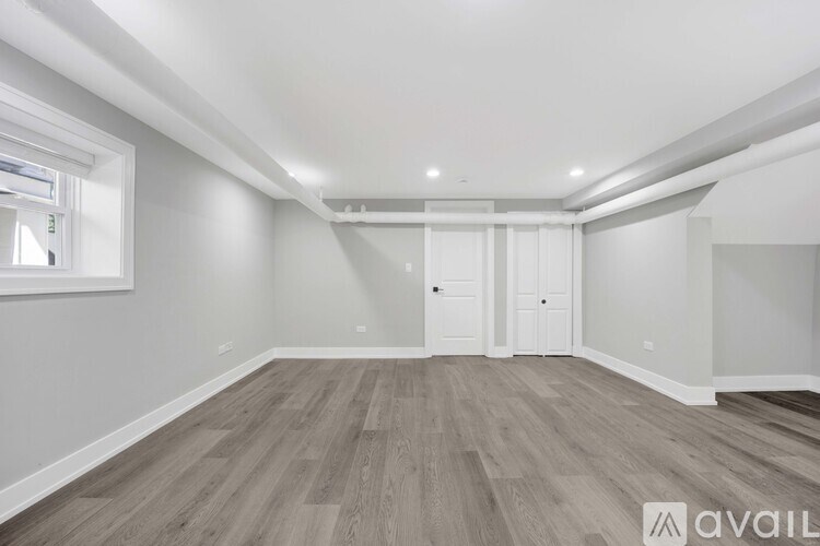 A spacious room with wooden flooring and white walls.