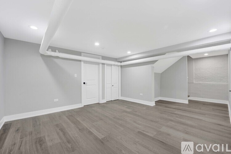 A spacious room with wooden flooring and white walls.