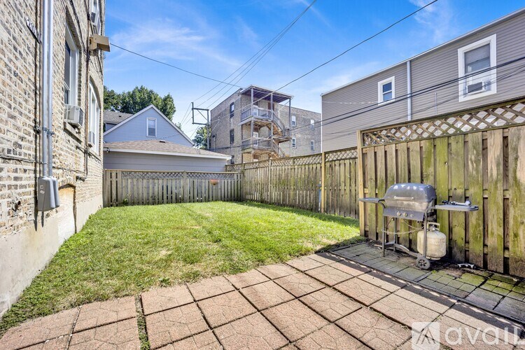 A backyard with a wooden fence and a grill.