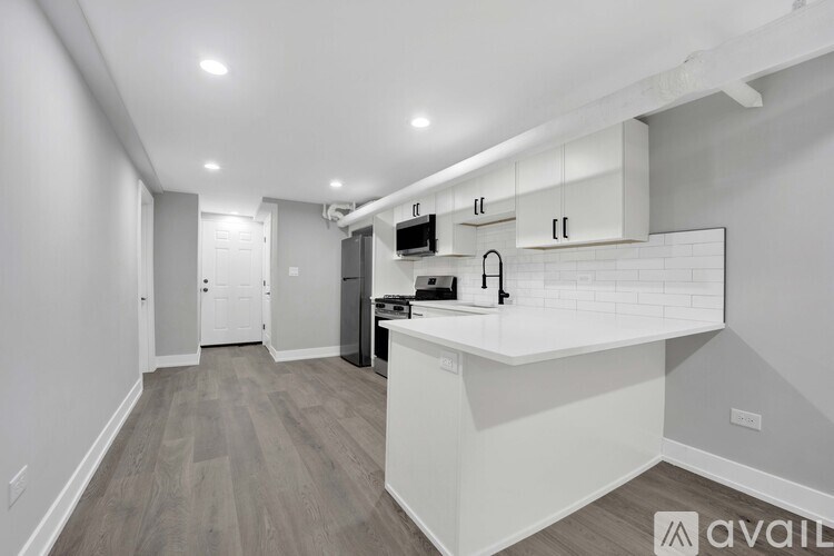 A modern kitchen with white cabinets and a wooden floor.