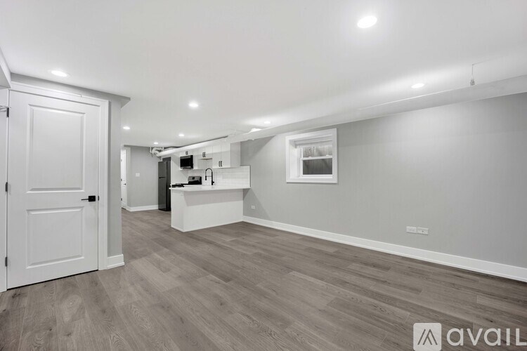 A spacious room with a white door and a wooden floor.
