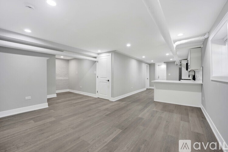 A spacious room with wooden flooring and white walls.