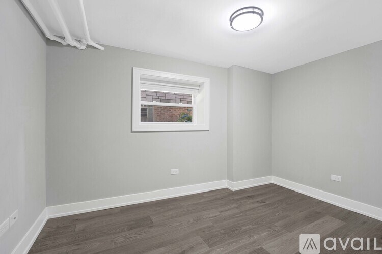 A room with a grey wall and a framed picture of a building on the wall.