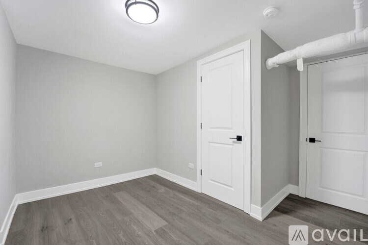 A room with a white door and a wooden floor.