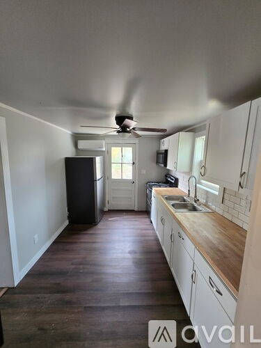 A kitchen with white cabinets and a black fridge.