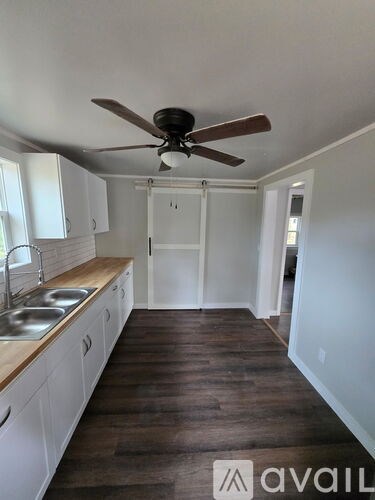A kitchen with a fan on the ceiling and wooden floors.