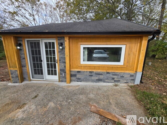 A small wooden house with a grey roof and a white door.