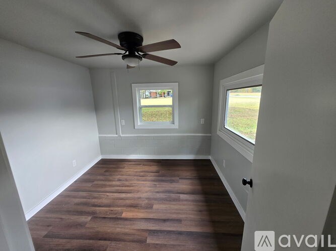 A room with a ceiling fan and wooden flooring.