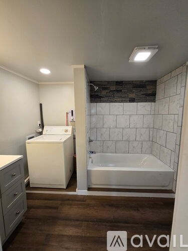 A bathroom with a white cabinet, a white sink, and a white bathtub.