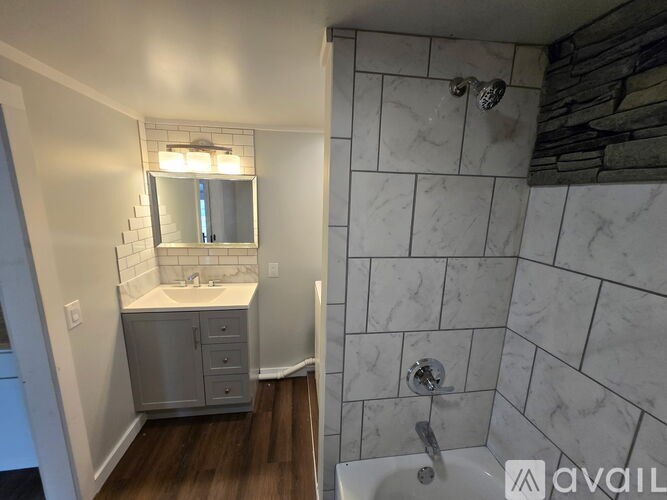 A bathroom with a marble tile shower and a white sink vanity with a mirror above it.