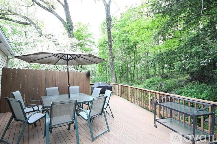 A table with chairs and an umbrella on a wooden deck.