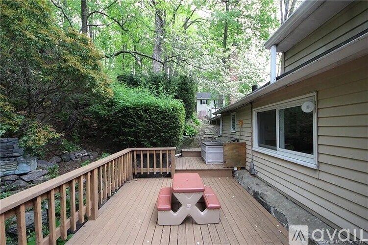 A wooden deck with a bench and picnic table in front of a house.