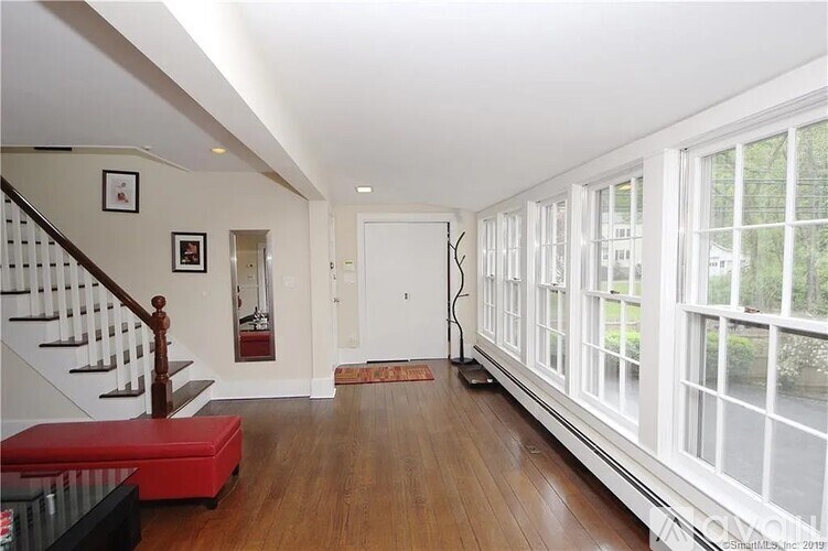 A long hallway with a red bench and a vacuum cleaner.