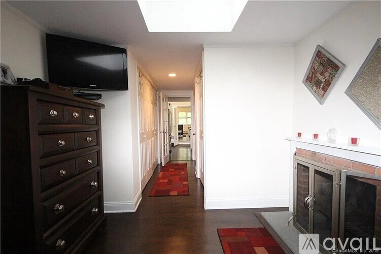 A long hallway with a red carpet and a fireplace on the right.