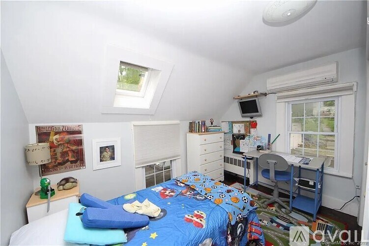 A bedroom with a bed, desk, and chair.