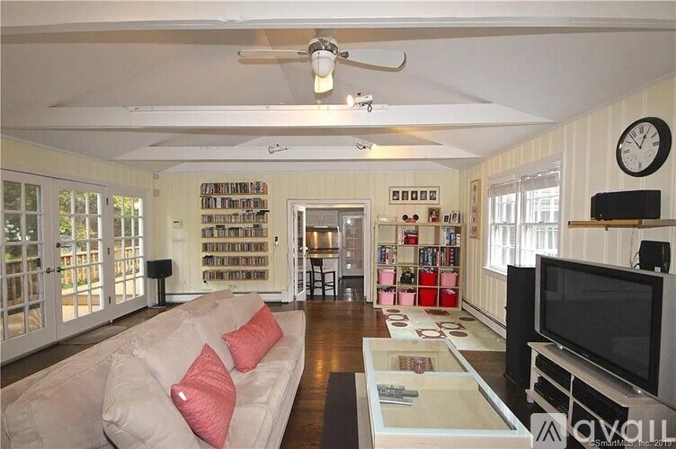 A living room with a couch, television, and bookshelves.