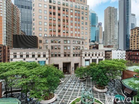 A courtyard surrounded by buildings with a green roof.